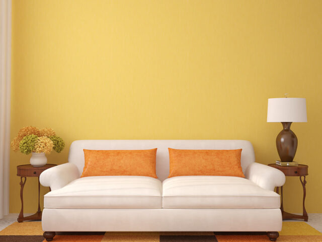 Sala de estar com sofa claro, mesas laterais e parede em tom quente