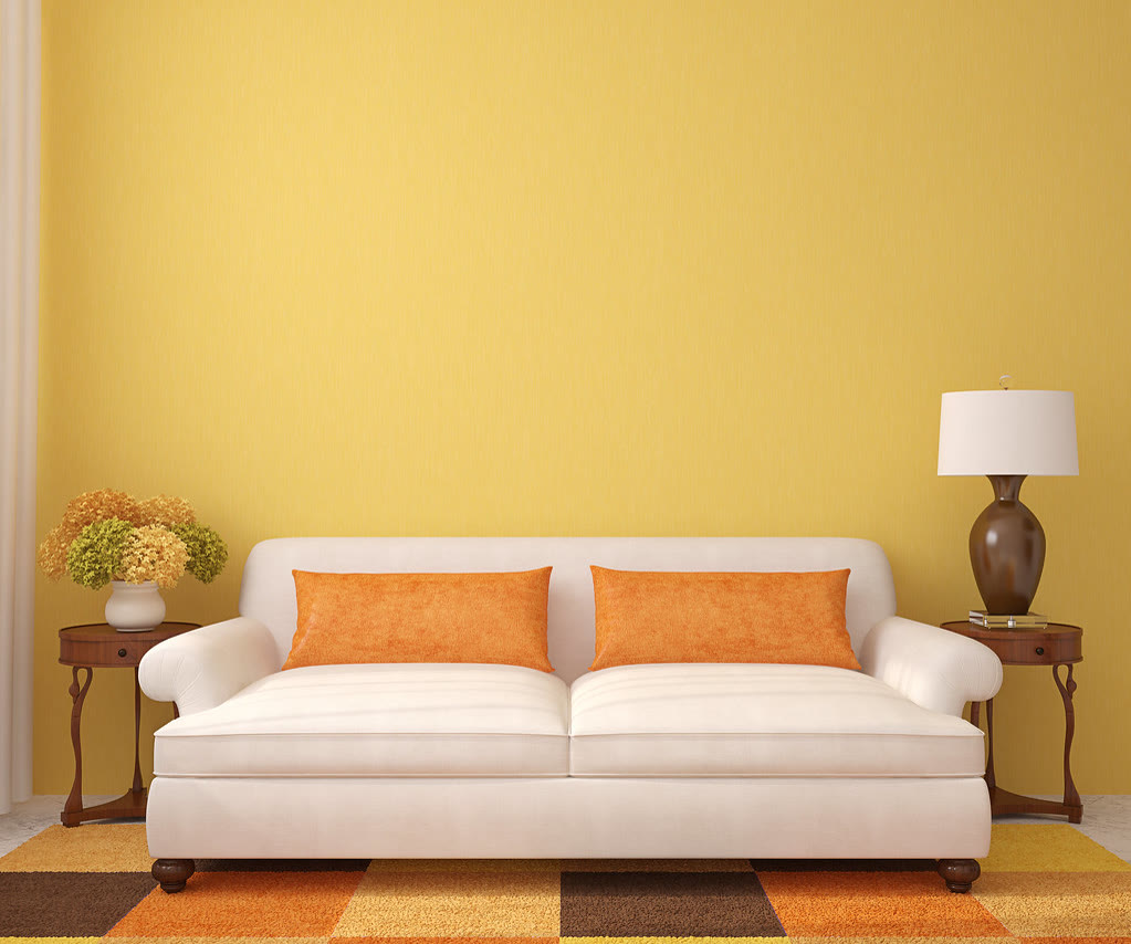 Sala de estar com sofa claro, mesas laterais e parede em tom quente